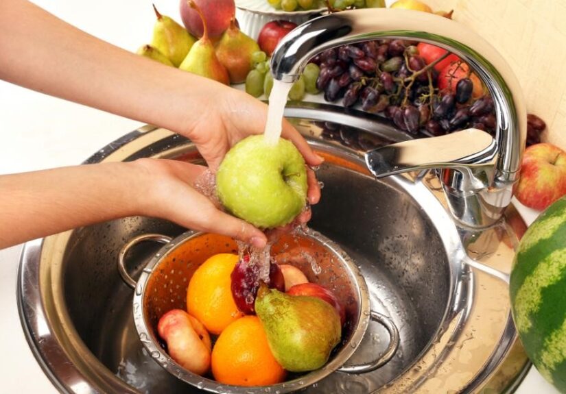 womans-hands-washing-apple-and-other-fruits-in-colander-in-sink-2BGW4RJ